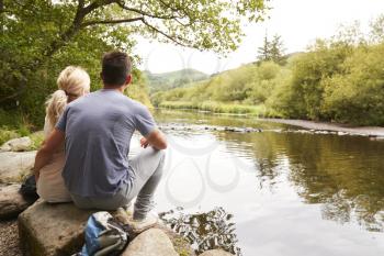 Couple On Hike Looking Out Over River In UK Lake District