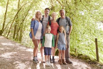 Portrait Of Multi Generation Family Enjoying Walk Along Woodland Path Together