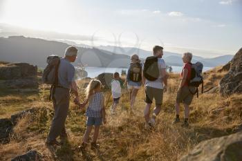Rear View Of Multi Generation Family Walking On Top Of Hill On Hike Through Countryside In Lake District UK
