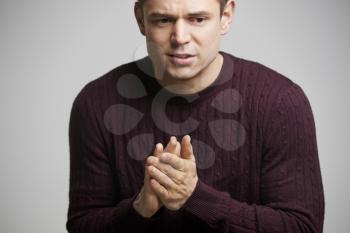 Nervous young white man rubbing his hands looking away, crop
