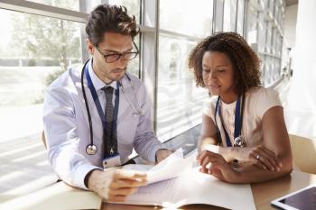 Male and female senior doctors reading patient notes