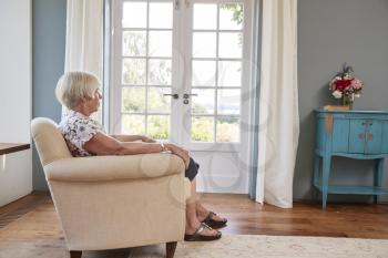 Senior woman sitting alone in an armchair at home