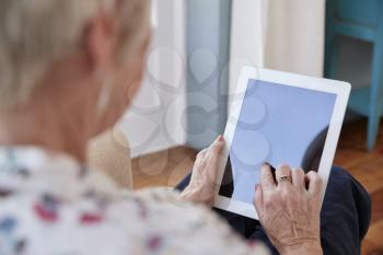 Senior woman using tablet computer, over shoulder view