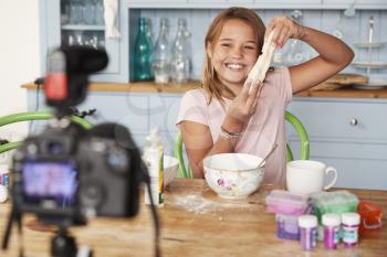 Young girl video blogging in a kitchen showing dough mixture