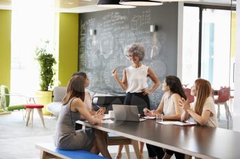 Female boss standing at an informal team meeting
