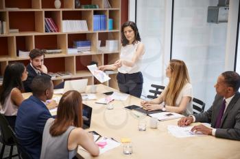 Female manager stands with document at boardroom meeting