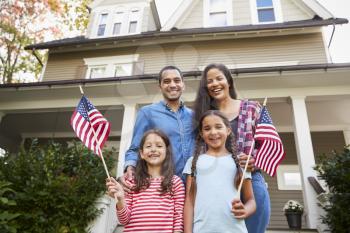 Portrait Of Family Outside House Holding American Flags
