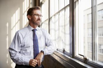 Senior businessman in shirt and tie looking out of window