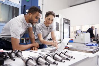 Two Engineers Using CAD Programming Software On Laptop