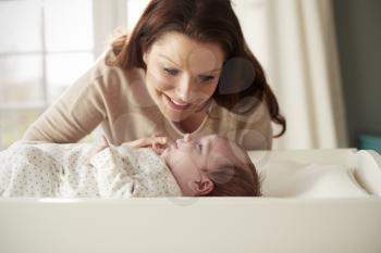 Mother With Newborn Baby Lying On Changing Table In Nursery
