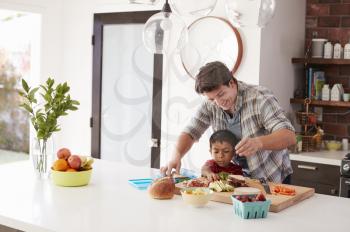 Father And Son Making School Lunch In Kitchen At Home
