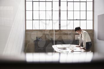 Businessman working alone in an office, seen through window