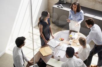 Female manager in team meeting, elevated view through window