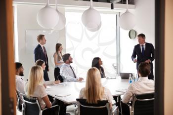 Mature Businessman Addressing Group Meeting Around Table At Graduate Recruitment Assessment Day