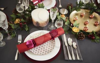 Close up of Christmas table setting with Christmas crackers arranged on plates, elevated view