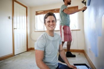 Portrait Of Two Men Decorating Room In New Home Painting Wall Together