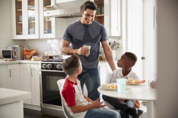 Dad standing in the kitchen talking with his son and a friend, who is over for a playdate