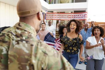 Three generation black family welcoming soldier returning home,over shoulder view, close up