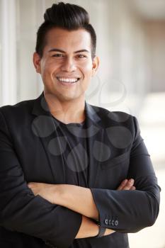 Portrait Of Smiling Male School Teacher Standing In Corridor Of College Building