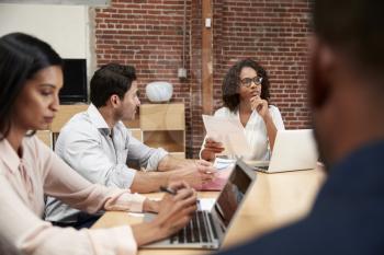 Businesswoman Leading Office Meeting Of Colleagues Sitting Around Table
