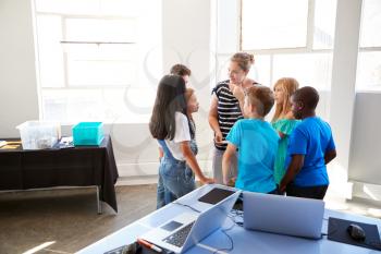 Teacher Talking With Group Of Students In After School Computer Class Learning To Code