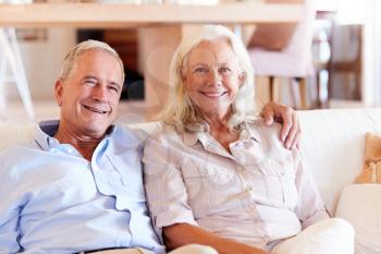 Senior white couple relaxing at home, smiling to camera, front view, close up
