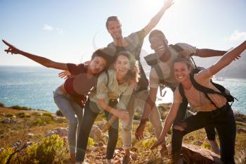 Millennial friends on a hiking trip reach the summit and have fun posing for photos