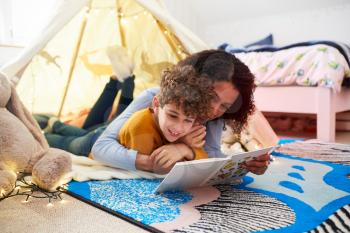 Single Mother Reading With Son In Den In Bedroom At Home