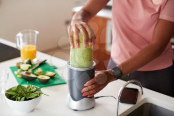 Close Up Of Woman Making Healthy Juice Drink With Fresh Ingredients In Electric Juicer After Exercise