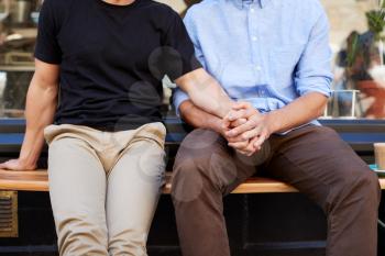 Close Up Of Male Gay Couple Sitting Outside Coffee Shop Holding Hands