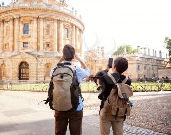 Male Gay Couple On Vacation Taking Photos Of Radcliffe Camera Building In Oxford On Mobile Phones
