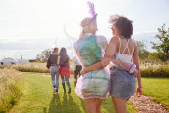 Rear View Of Female Friends Walking Back To Tent After Outdoor Music Festival