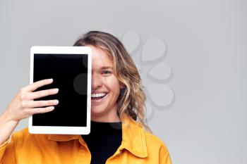 Studio Portrait Of Smiling Young Woman Covering Face With Digital Tablet