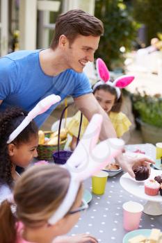 Father With Children Wearing Bunny Ears Enjoying Outdoor Easter Party In Garden At Home