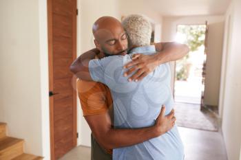 Loving Senior Father Hugging Adult Son Indoors At Home