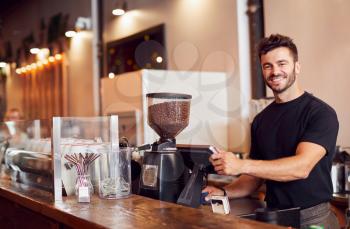 Portrait Of Male Coffee Shop Owner Standing At Sales Desk