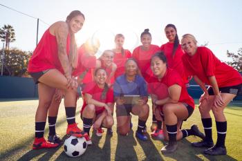 Portrait Of Coach Holding Digital Tablet With Womens Football Team Training For Soccer Match