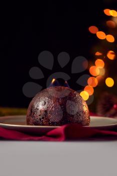 Brandy Soaked Christmas Pudding With Flames On Table Set For Festive Christmas Meal