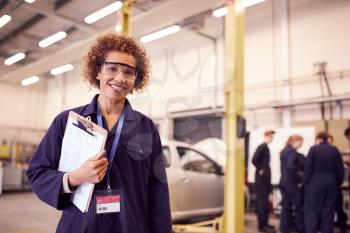 Portrait Of Female Tutor With Safety Glasses Teaching Auto Mechanic Apprenticeship At College