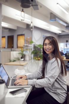 Portrait Of Businesswoman Working On Laptop In Kitchen Area Of Modern Office