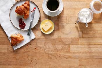 Overhead Flat Lay Shot Of Table Laid For Breakfast Croissant And Coffee