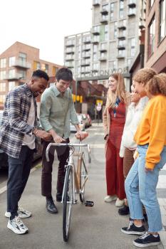 Group Of Multi-Cultural Friends Walking On City Street With Sustainable Bamboo Bicycle