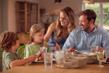 Family Sitting Around Table At Home Enjoying Meal Together