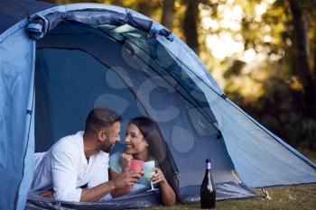 Camping Couple Lying In Tent Drinking Champagne Together