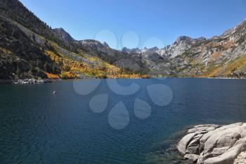 Mountain fishing lake with transparent azure water. Solar autumn midday