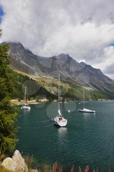 Beautiful mountain Swiss lake. Magnificent sailing yachts are reflected in water