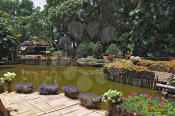 Wonderful quiet pond in the green tropical park. The pond is surrounded by flowerbeds