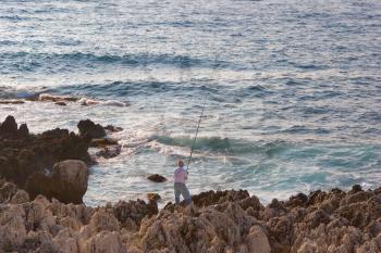  The fisherman with a fishing tackle on coast of Mediterranean sea.