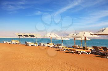 Beautiful sunny day at a beach resort. Dead Sea, the orange sand and beach chairs waiting for tourists