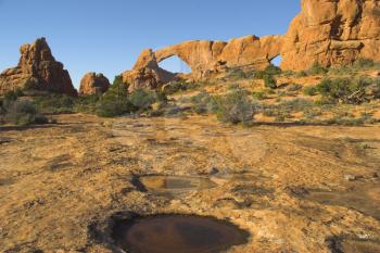 Two arches and small pool in a huge natural stone wall in National park  Arches in the USA